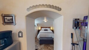 Habitación de hotel con cama, mesitas de noche, pequeño banco, calentador de pared y un cuadro en la pared.