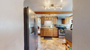 Una cocina moderna con armarios de madera, un refrigerador de acero inoxidable, horno empotrado y estufa a gas.