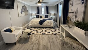 A bedroom with a bed, a TV mounted on the wall, a ceiling fan, and a large window with curtains. - ☀️WOW☀️ UPDATED with HEATED POOL & HOT TUB HOME 5 MIN TO BEACH 3BD 2BA 2 KING BEDS (Seminole)