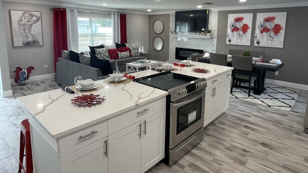 A modern kitchen with white cabinetry, stainless steel appliances, and a dining area with a table set for four. - ☀️WOW☀️ UPDATED with HEATED POOL & HOT TUB HOME 5 MIN TO BEACH 3BD 2BA 2 KING BEDS (Seminole)
