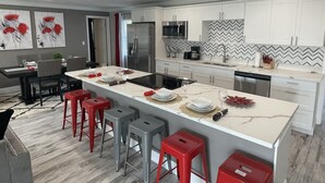 A modern kitchen with white cabinets, a large island with bar stools, a microwave, and a dishwasher. - ☀️WOW☀️ UPDATED with HEATED POOL & HOT TUB HOME 5 MIN TO BEACH 3BD 2BA 2 KING BEDS (Seminole)