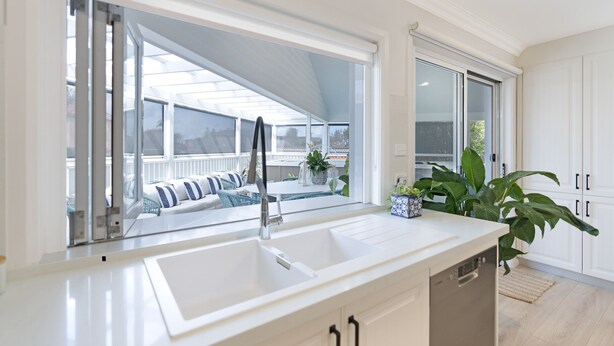 Eine moderne Küche mit großem Fenster, integriertem Spülbecken und Blick auf eine Terrassenanlage.
