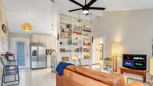 A modern living room with a leather sofa, a dining area with bar stools, a kitchen with a built-in fridge, and a TV displaying streaming services. - Quick Bike Ride to Central Austin from Quiet 1BD (Austin)
