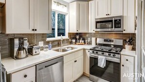 A modern kitchen with white cabinets, stainless steel appliances, and a window providing natural light. - Quick Bike Ride to Central Austin from Quiet 1BD (Austin)