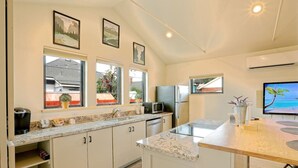 A modern kitchen with a large island, built-in appliances, and a view of the outdoors through large windows.