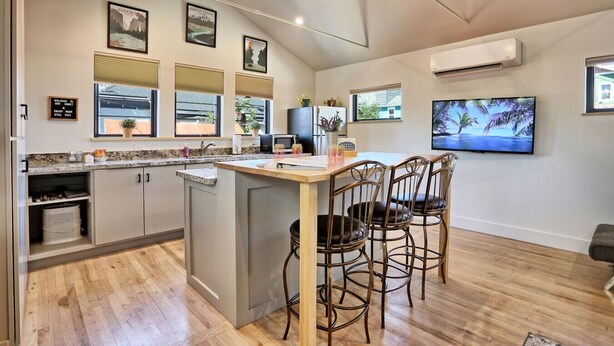 A modern kitchen with a central island, built-in appliances, and a dining area with chairs.