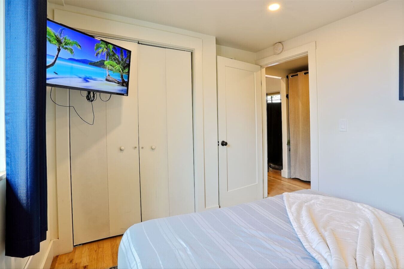 Une chambre à coucher avec un lit, un téléviseur fixé au mur et une armoire.