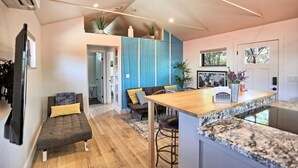 A modern kitchen with a wooden island, blue cabinets, and a dining area with a sofa and chairs.