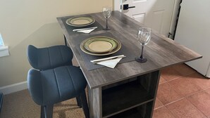 A dining table set with plates, cutlery, and glasses, flanked by two chairs, in a room with a door and light switch on the wall. - Paradise in The Parks on Westside with summer pool, bike trails and restaurants. (Bend)