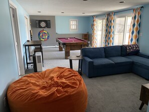A living room with a pool table, a blue sofa, and an orange bean bag. - Relaxing Pond Front Home (Forestdale)