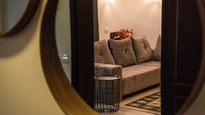 Una sala de estar moderna con un sofá gris, una mesita redonda pequeña y un jarrón decorativo en la pared.