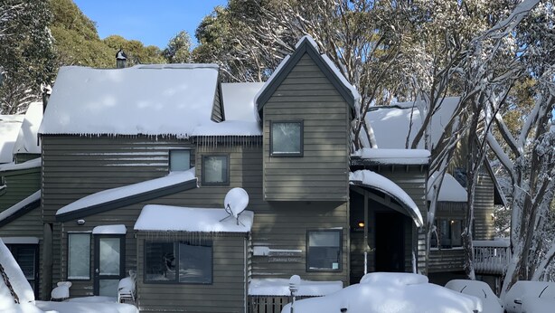 A two-story wooden house with a snow-covered roof and driveway, a satellite dish, and a sign indicating parking is for Faithful's only. - Charming Alpine Chalet 'Faithfulls' at Dinner Plain - Pet Friendly (Dinner Plain)