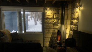 A cozy room with a stone fireplace, a window overlooking a snowy landscape, and a comfortable seating area. - Charming Alpine Chalet 'Faithfulls' at Dinner Plain - Pet Friendly (Dinner Plain)