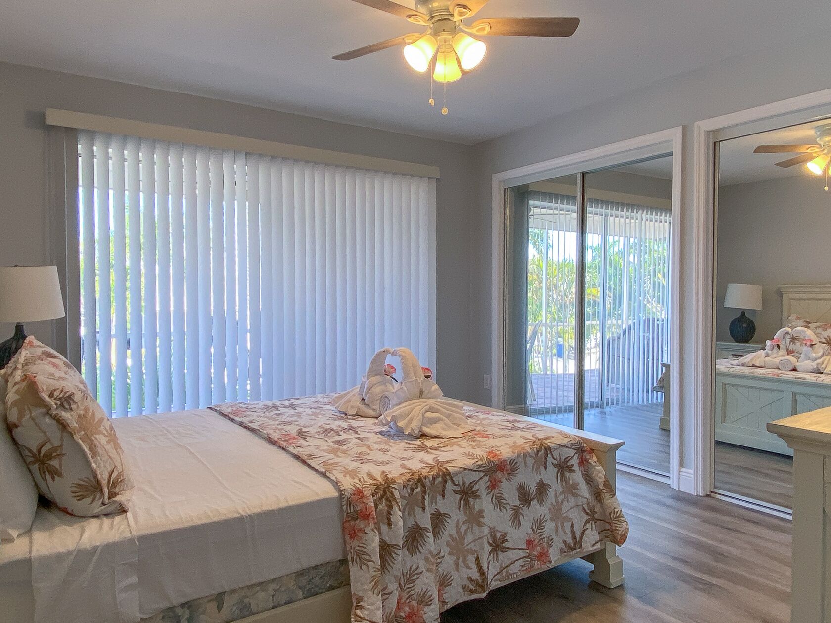 A bedroom with a bed, a ceiling fan, and a view of the outside through a sliding glass door.