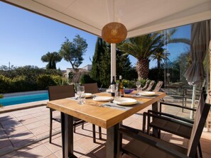 An outdoor dining area with a table set for four, overlooking a swimming pool and lush greenery. - Harmony by Interhome (Jávea)