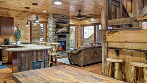 A rustic cabin interior with a stone fireplace, wooden ceiling, and a cozy seating area. - Near Dollywood! Beautiful Mountain Views, Hot Tub & Resort Indoor Heated Pool (Sevierville)