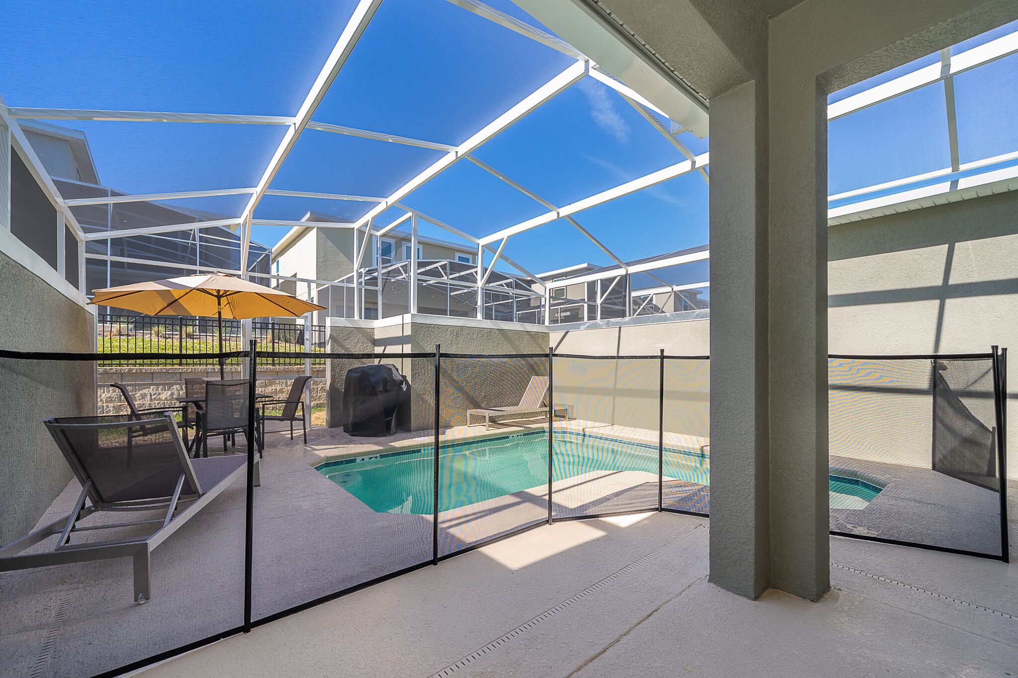 Ein überdachter Poolbereich im Freien mit Liegestühlen und einem Sonnenschirm.
