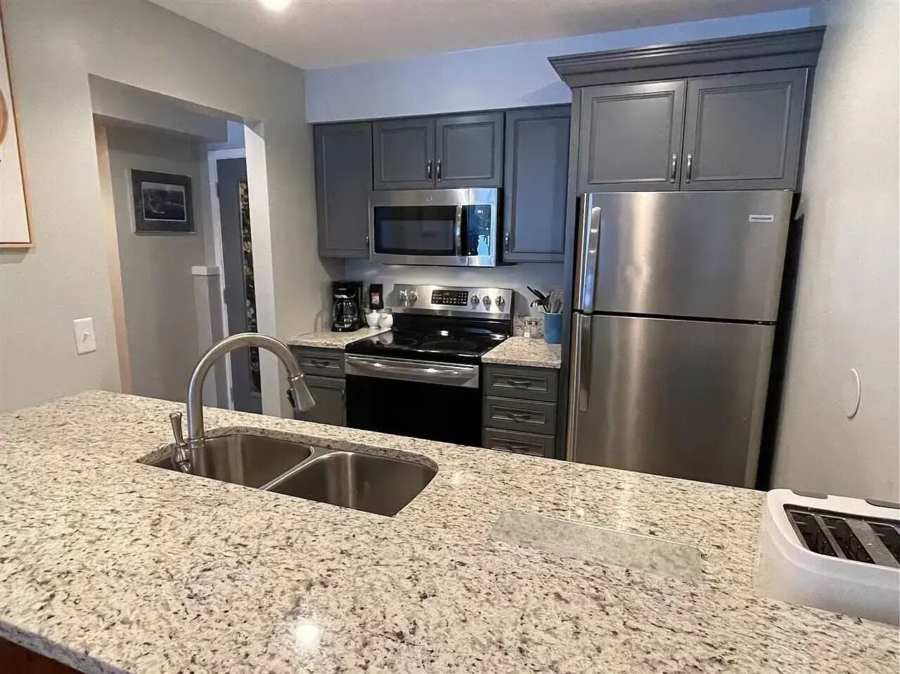 A kitchen with granite countertops, stainless steel appliances, and a double sink.