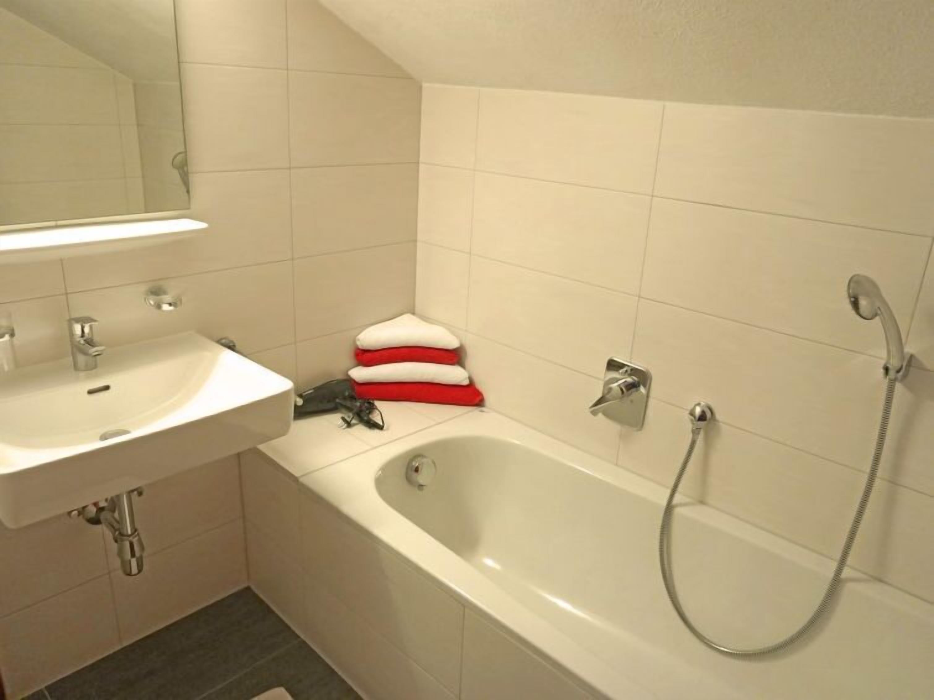 A bathroom with a white sink, a bathtub, and a shower.