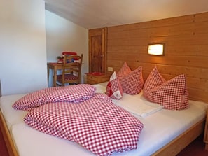 A bed with red and white checkered bedding, a wooden headboard, and a small bedside table with a lamp.