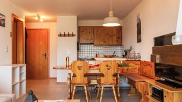 Un espace de vie compact comprenant un coin repas, une cuisine et un coin salon.