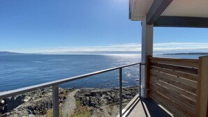 A balcony with a view of the ocean and rocky coastline. - 10 Mile Point Surfside Suite (Victoria)