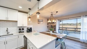 A modern kitchen with white cabinets, a large island, and pendant lighting.