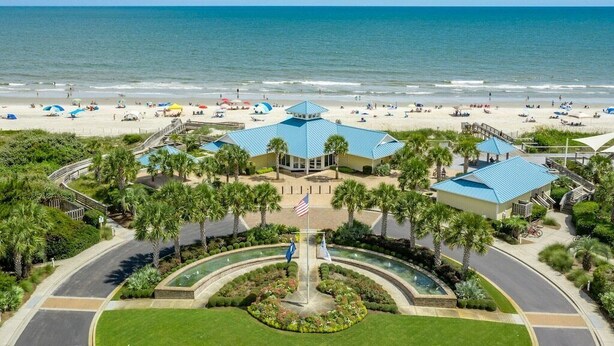 A beachfront hotel with a central courtyard, palm trees, and a view of the ocean.