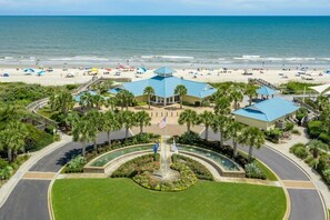 Ein Strandhotel mit Innenhof, Palmen und Meerblick.