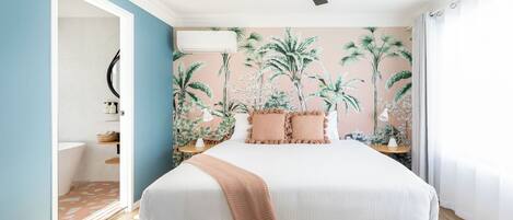 A bedroom with a bed, a ceiling fan, a wall-mounted air conditioner, and a window with curtains.