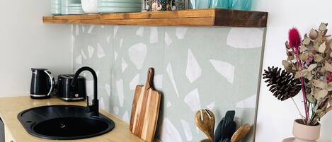 A modern kitchen with a black sink, wooden countertop, and decorative items including a vase with dried flowers.
