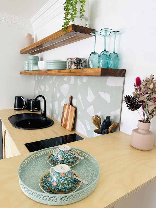 A modern kitchen with a black sink, wooden countertop, and decorative items including a vase with dried flowers. - Tessa's on the Beach Boutique Hotel (Bilinga)