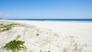 A beach with white sand and sparse vegetation.
