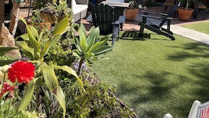 Un jardín bien cuidado con césped, muebles de patio y una silla colgante.