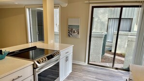 A kitchen with a built-in oven, a stovetop, and a sliding glass door leading to a balcony.