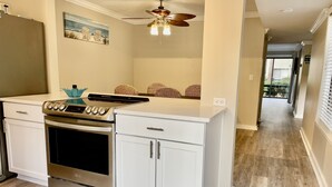 A modern kitchen with white cabinetry, a stainless steel oven, and a ceiling fan.