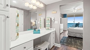 A bedroom with a bed, a desk with a mirror, a ceiling fan, and a view of the ocean. - Stay Majestic! 3BR w/ Gulf Views, Balcony & Pools (Panama City Beach)