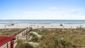 A beach with a wooden walkway leading to the shore, a lifeguard tower, and beach umbrellas. - Stay Majestic! 3BR w/ Gulf Views, Balcony & Pools (Panama City Beach)