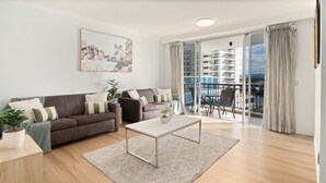 Una sala de estar moderna con un juego de sofá, una mesa de centro y un balcón con mobiliario exterior.