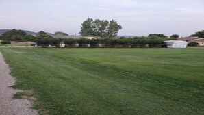 A well-maintained grassy area with a gravel path, surrounded by residential houses and trees. - Tent Camping for Sturgis Rally 1 (Sturgis)