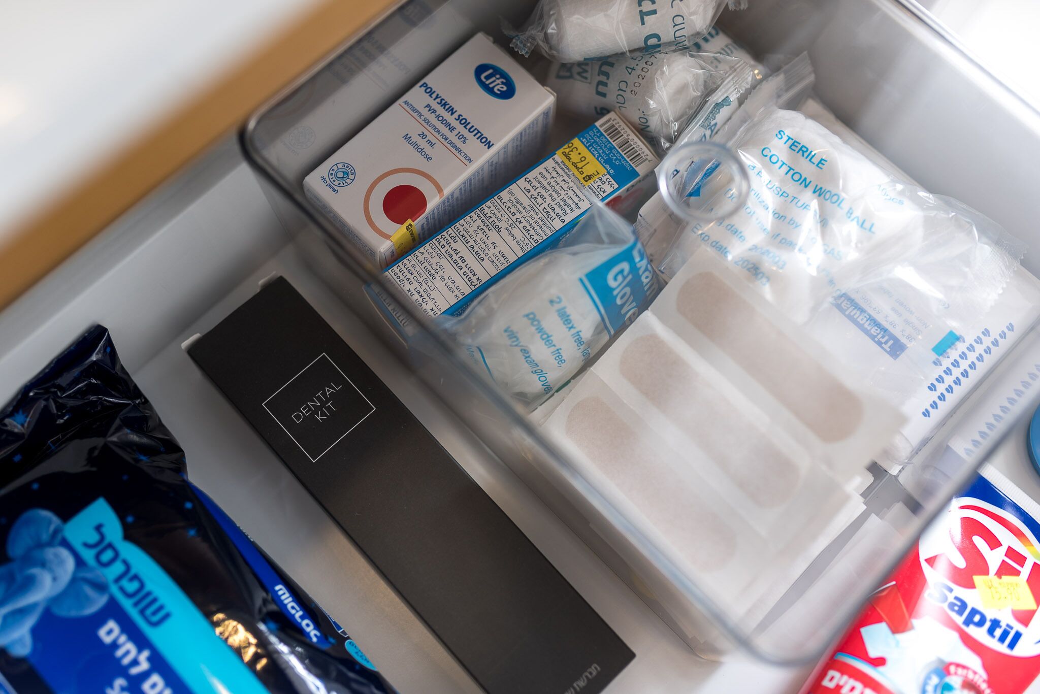 A dental kit with various items including a box of Life Polyskin Solution, sterile cotton wool balls, and a can of Saptil.