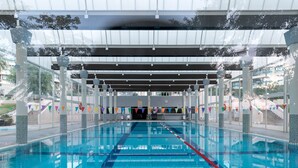 Ein Hallenbad mit deutlich markierten Bahnen, überdachtem Bereich und Blick ins Freie.
