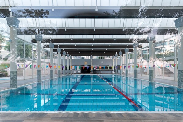 An indoor swimming pool with clear lanes, a covered area, and a view of the outside.