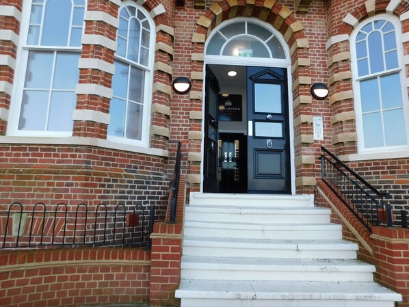 A brick building with a black door, white steps, and a sign that reads "URLINGTON". - With its wonderful, far reaching sea views, this first floor apartment certainly does have the WOW f (Sheringham)