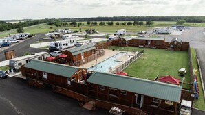 A campground with RVs, a pool, and wooden cabins. - Do Drop Inn RV Resort and Cabins (Cartwright)