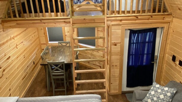 A cozy cabin with a loft bedroom, a dining area, and a sofa. - Do Drop Inn RV Resort and Cabins (Cartwright)