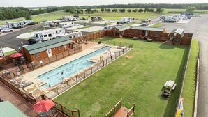 A recreational area with a swimming pool, deck chairs, and a fenced-in grassy area. - Do Drop Inn RV Resort and Cabins (Cartwright)