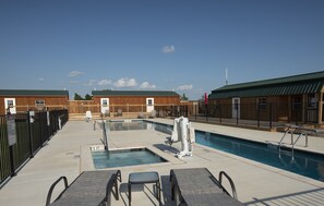 Uma área de piscina com trampolim, espreguiçadeiras e uma pequena banheira de hidromassagem.