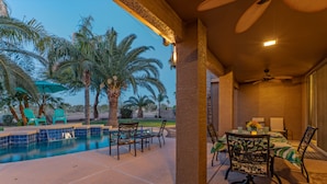 A covered outdoor area with a pool, chairs, and a table with a vase of flowers. - Golf Course VIEW: Htd POOL, Hot Tub, Fire Pit, Game Room w/Pool Table, TVs All BRs, 2 Kid's Bikes (Gilbert)