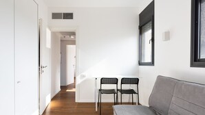 Un salon moderne avec un canapé gris, deux fauteuils noirs et une table blanche.